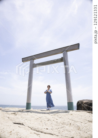 海岸沿いの鳥居の前に立つ女性 129121331