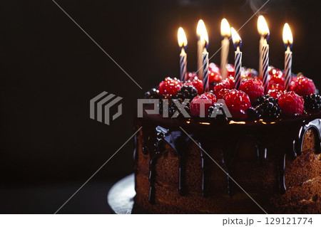 Birthday cake decorated with chocolated frosting, berries and  birthday candles. 129121774