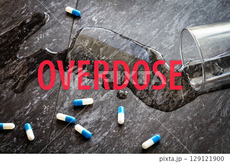The inscription overdose on the background of scattered pills and spilled water. 129121900