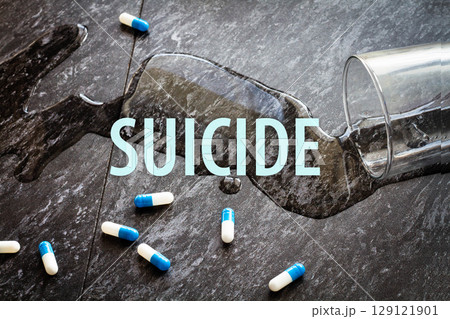 The inscription suicide on the background of scattered pills and spilled water. The inscription suicide on the background of scattered pills and spilled water. 129121901