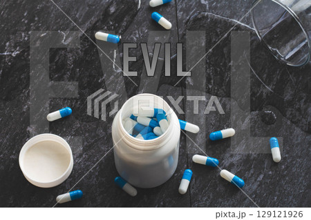 The inscription evil on the background of pills on a black table. The inscription evil on the background of pills on a black table. 129121926
