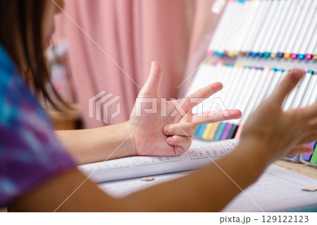 Two elementary school girls are studying at their desks at home. Two cute schoolgirls are diligently doing their homework. 129122123