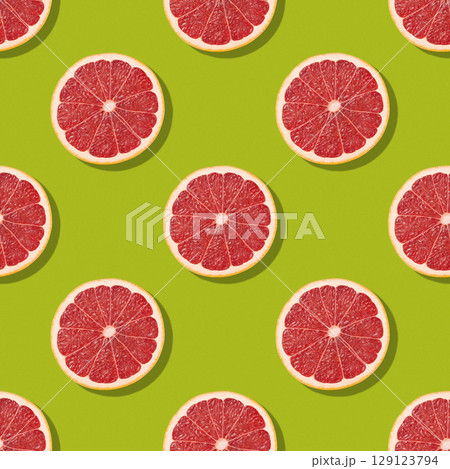 Colorful citrus food background. Seamless pattern of colorful grapefruit slices on light green background. Creative fruits concept. Colorful citrus food background. Seamless pattern of colorful grapefruit slices on light green background. Creative fruits concept. 129123794