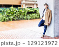 Stylish young man in coat and scarf outdoors 129123972