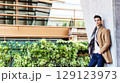 Stylish young man in coat and scarf outdoors 129123973