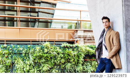 Stylish young man in coat and scarf outdoors 129123973