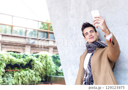 Young man taking selfie outdoors in winter outfit 129123975