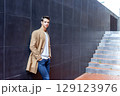 Stylish man leaning on wall with modern stairs 129123976