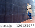Stylish man leaning on wall with modern stairs 129123977