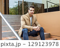 Confident young man sitting on modern outdoor steps 129123978