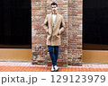 Stylish man posing against brick wall in urban setting 129123979
