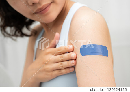HPV, Human papillomavirus, Asian young woman receiving vaccine with blue bandage. HPV, Human papillomavirus, Asian young woman receiving vaccine with blue bandage. 129124136