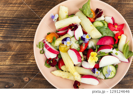 A bowl of mixed greens salad with edible flowers. A bowl of mixed greens salad with edible flowers. 129124646