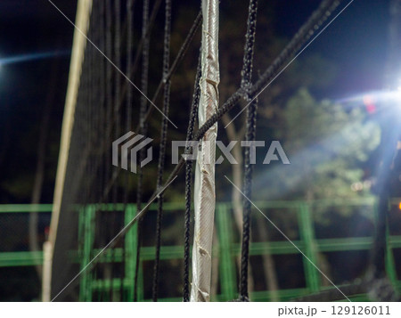 Beach volleyball court in the evening. Available infrastructure. Empty sports ground. Volleyball game concept. Sports mesh. Entertainment in the park.   Under the lanterns 129126011