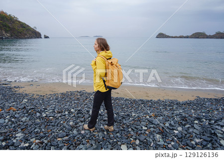 Woman walking near cloudy winter sea 129126136