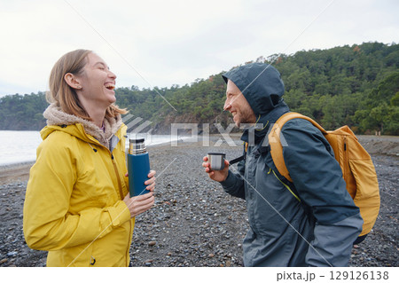 Couple drinks tea by winter sea shore 129126138