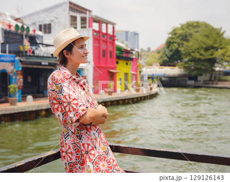 woman in dress and hat exploring vibrant streets of Malacca, Malaysia. 129126143