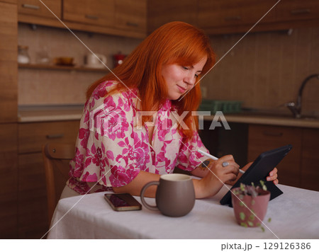 young woman working on tablet at kitchen 129126386