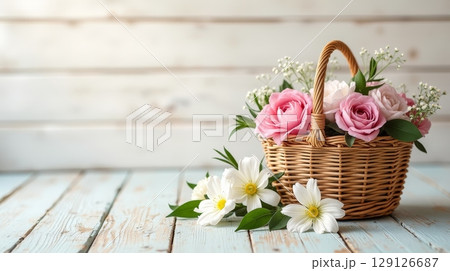 Wicker basket with pink roses and white flowers on rustic wooden table. Floral arrangement with copy space. Spring and romantic concept Wicker basket with pink roses and white flowers on rustic wooden table. Floral arrangement with copy space. Spring and romantic concept 129126687
