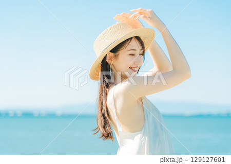 海と青空バックの麦わら帽子を被った女性 129127601