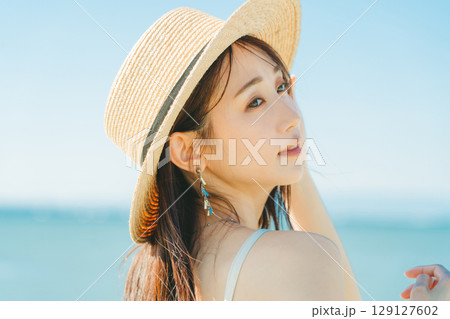海と青空バックの麦わら帽子を被った女性 129127602