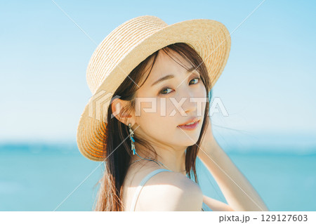 海と青空バックの麦わら帽子を被った女性 129127603