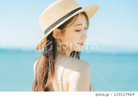 海と青空バックの麦わら帽子を被った女性 129127604