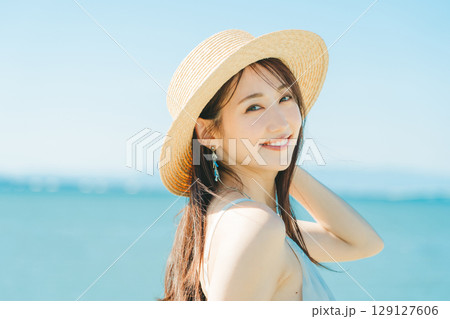 海と青空バックの麦わら帽子を被った女性 129127606