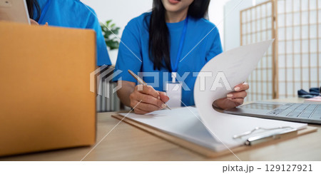 Volunteer writing notes for donation management in community service Volunteer writing notes for donation management in community service 129127921