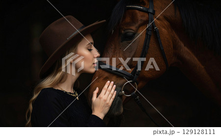A young woman gently kisses a horse's face at sunset, capturing an intimate moment of trust and connection. The soft backlight highlights their bond in a serene countryside setting A young woman gently kisses a horse's face at sunset, capturing an intimate moment of trust and connection. The soft backlight highlights their bond in a serene countryside setting 129128111