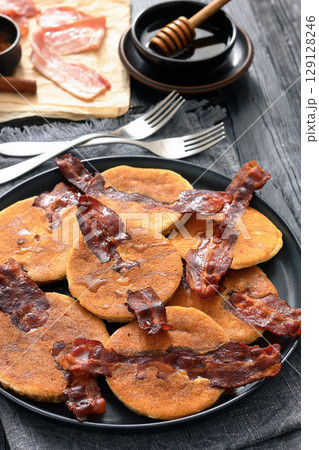 bacon pancakes drizzled with sirup on a plate 129128246