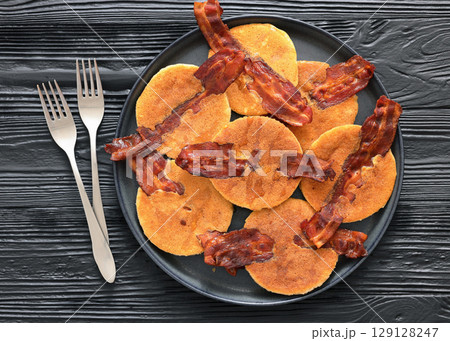 bacon pancakes drizzled with sirup on a plate 129128247