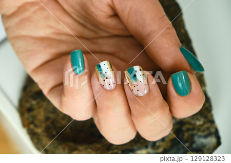Female hands with green nail design. 129128323