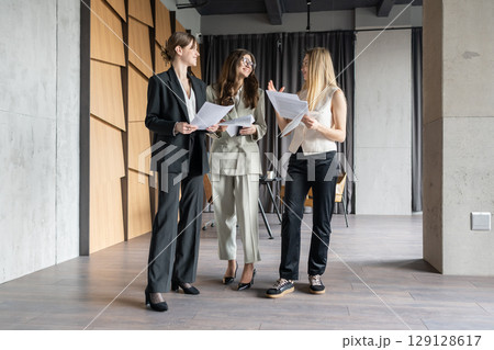 Businesswomen having a casual conversation in a modern office lobby 129128617