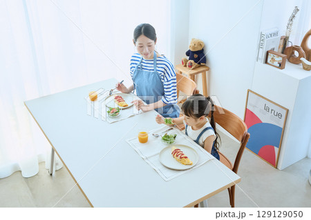 子どもの食事を見守る母と娘のあたたかい朝食 129129050