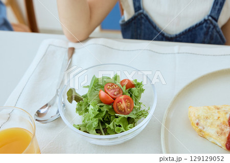 サラダを食べる女の子の健康的な食卓風景 129129052