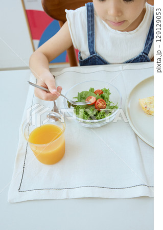 サラダを食べる女の子の健康的な食卓風景 129129053