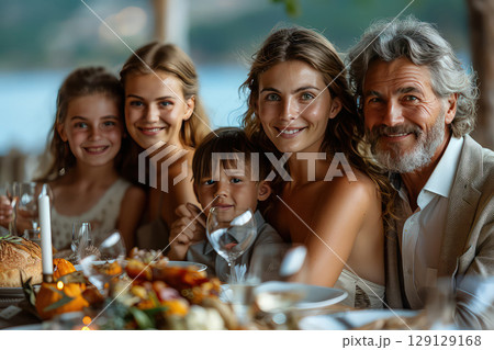 A family gathering around the table for a multi-generational dinner. Generations come together, bonding over a delicious meal. 129129168