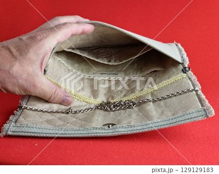 Handmade retro clutch bag on a red background. Vintage bag on chain handle. Inside the bag is trimmed with silk fabric and embroidered with beads. 129129183