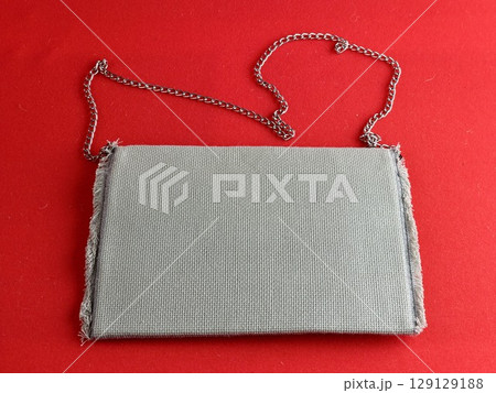 Handmade retro clutch bag on a red background. Vintage bag on a chain handle. 129129188