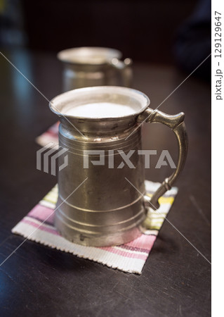 Vintage Japanese metal beer mugs filled with beer, photographed on a dark wooden table Vintage Japanese metal beer mugs filled with beer, photographed on a dark wooden table 129129647
