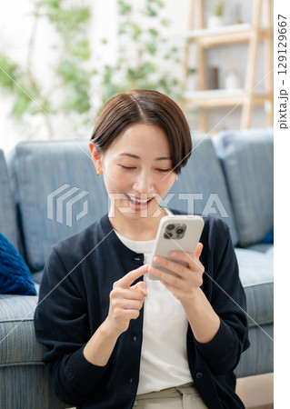 リビングでスマホを見る女性 リビングでスマホを見る女性 129129667