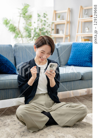 リビングでスマホを見る女性 リビングでスマホを見る女性 129129668