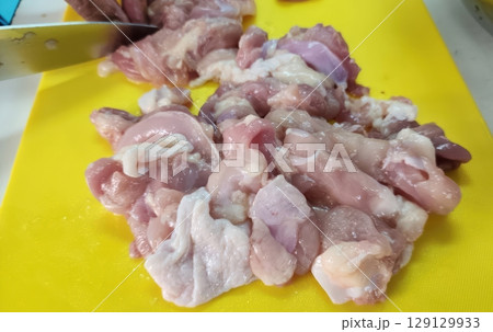 Raw Chicken Pieces on Yellow Cutting Board with Knife for Cooking in Kitchen Environment 129129933
