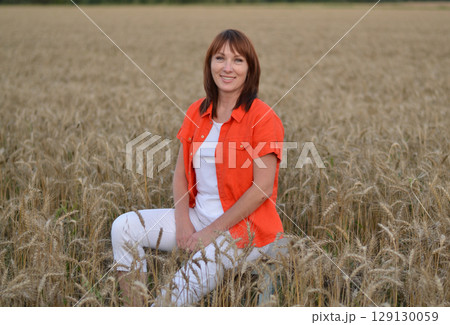 Woman meditating while sitting cross-legged in a golden wheat field during sunset hours for a sense of peace and tranquility Woman meditating while sitting cross-legged in a golden wheat field during sunset hours for a sense of peace and tranquility 129130059