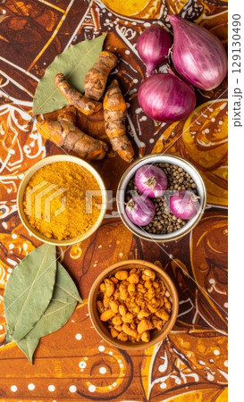 Overhead Shot Featuring Turmeric Red Onions and Bay Leaves on Floral Backdrop 129130490
