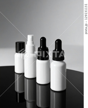 Four White and Black Topped Cosmetic Bottles on Black Reflective Surface 129131131