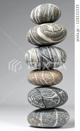 Balanced Stack of Decorative Striped Stones on a Soft Gray Seamless Background 129131535