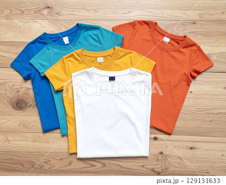 Pile of Colorful T Shirts Folded on Wood Table Surface Background 129131633