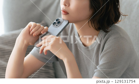 スマートフォンを持って考えごとをする女性 129131754